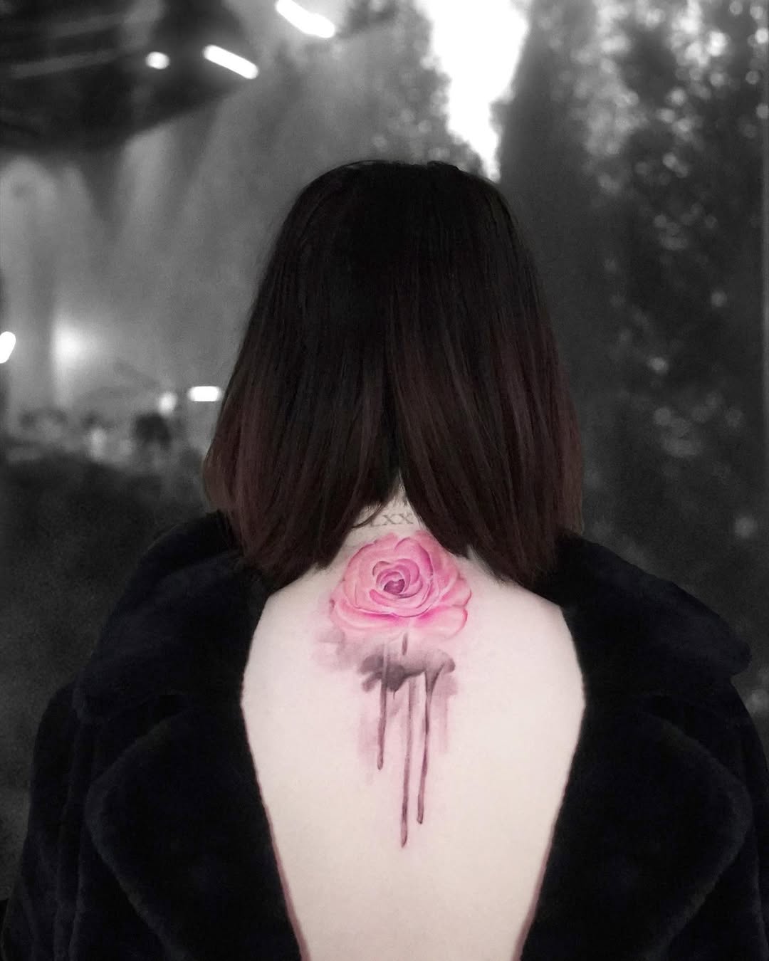 Source photo of Selena Gomez seen from behind with a pink watercolor rose tattoo and dark drip-like marks at the center of her upper back